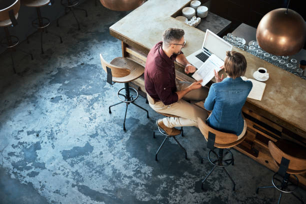High angle shot of two businesspeople working at the bar in a cafe